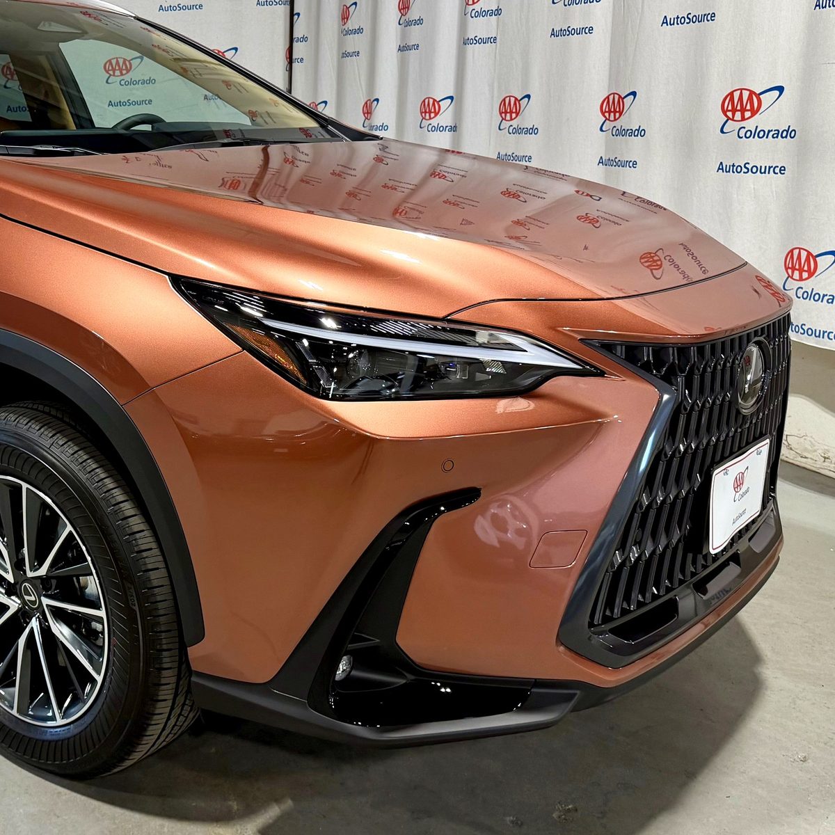 A new Lexus NX ready for delivery in front of the AAA Colorado AutoSource backdrop
